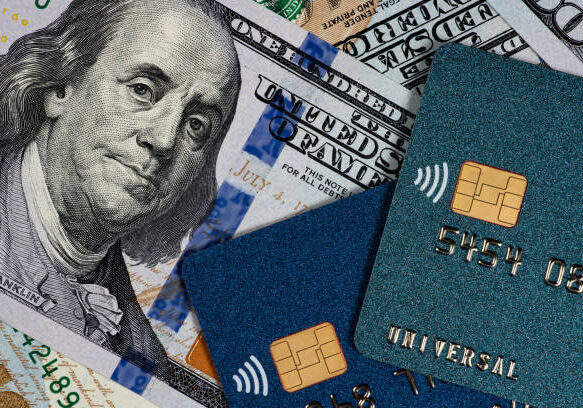 Close-up of US hundred dollar bills and contactless credit cards showing EMV chips and wireless payment symbols