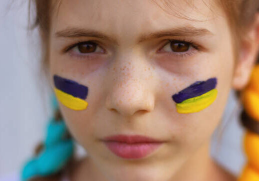 Close-up portrait of a young person wearing Ukrainian flag face paint stripes under their eyes.