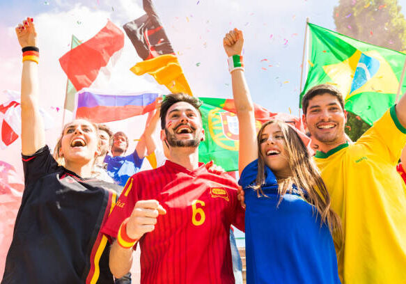 International soccer fans celebrating with flags of different countries, wearing team jerseys and cheering with raised arms