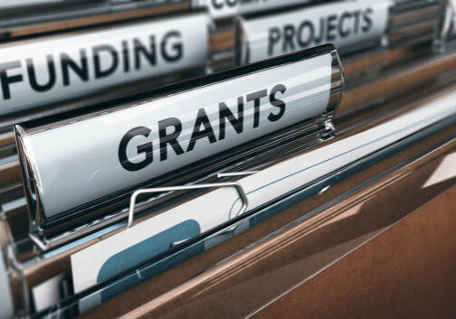 Close-up of file folder tabs labeled "FUNDING," "PROJECTS," and "GRANTS" in a filing system