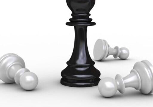 A black king chess piece stands upright while several white pawns lie fallen around it, symbolizing victory or dominance.