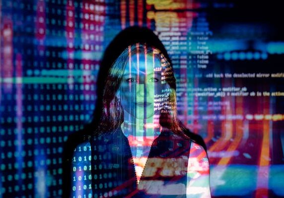 Woman's face overlaid with digital code and colorful tech projections in cybersecurity concept image