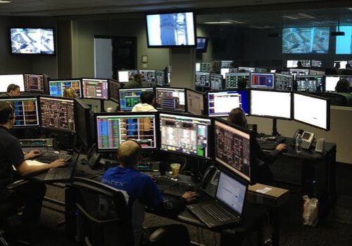 Trading floor operations room with multiple computer monitors displaying financial data and market information screens