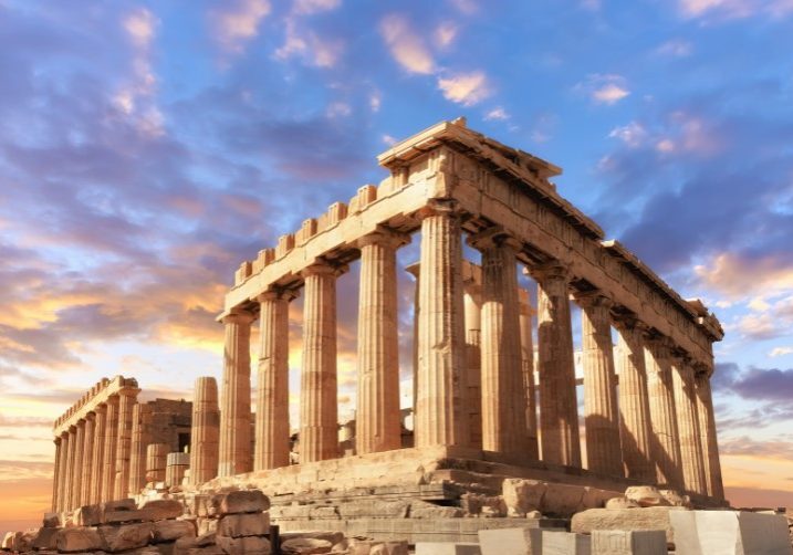 Ancient Parthenon temple on Athens Acropolis with Doric columns silhouetted against dramatic purple and orange sunset sky